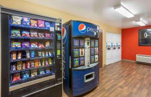 una máquina de soda de cocacola en una tienda al lado de un enfriador de bebidas en Extended Stay America Suites - Columbia - Stadium Blvd en Columbia