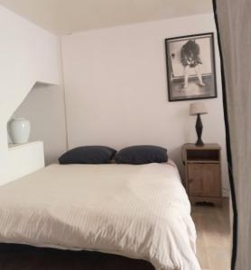 - une chambre avec un lit blanc et une photo sur le mur dans l'établissement Le Nid, à Avignon