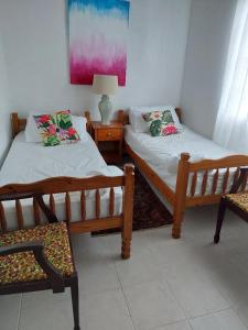 two beds in a room with two chairs and a lamp at Selen's Apartment in Ti Rocher Micoud Saint Lucia in Micoud