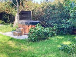 a wooden hot tub and a bench in the grass at 5 person holiday home in V ggerl se in Marielyst