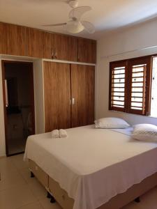 a bedroom with a large white bed with wooden cabinets at Barcelona Beach Residence in Canoa Quebrada