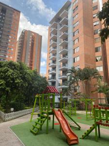 un parque infantil con tobogán en un parque con edificios altos en La Sabana, en Sabaneta