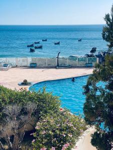 a swimming pool with the ocean in the background at Appartement vue sur mer in Agadir