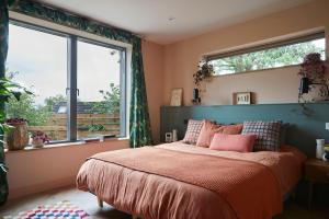 sypialnia z dużym łóżkiem i 2 oknami w obiekcie Nuthatch Retreat - Modern rustic ecohome with views w mieście Blakeney