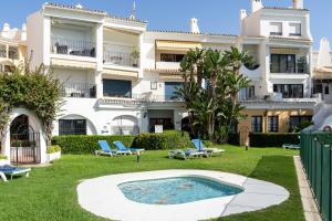 an apartment building with a swimming pool in the yard at Beachfront Puerto Cabopino in Marbella
