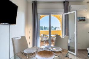 une salle à manger avec une table, des chaises et une télévision dans l'établissement Beachfront Puerto Cabopino, à Marbella