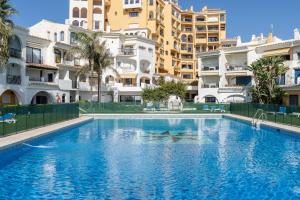 a swimming pool in front of some apartment buildings at Beachfront Puerto Cabopino in Marbella