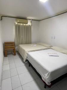 - une chambre avec 2 lits et une table dans l'établissement Pousada Cactus, à Barreirinhas