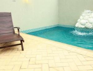 a swimming pool with a bench and a chair in a room at Apartamento Central - Andar alto in Joinville