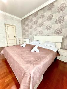 1 dormitorio con 1 cama rosa y 2 toallas en "3-Bedroom Charming Apartment in Central Almaty", en Almaty