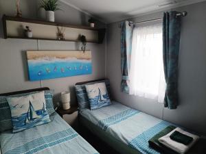 a bedroom with two beds and a window at Haven Rockley Park, Lytchett Bay View, Private Holiday Home - Caravan in Lytchett Minster