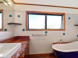 łazienka z wanną, umywalką i oknem w obiekcie The Terrace Lake Tarawera w mieście Lake Tarawera
