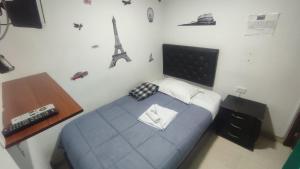 1 dormitorio con cama azul y mando a distancia en Hotel Palma de la Sabana, en Bogotá