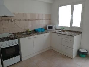 a kitchen with white cabinets and a sink and a microwave at Rukan in Comodoro Rivadavia
