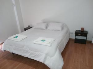 a white bed with two towels on top of it at Rukan in Comodoro Rivadavia
