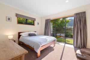 Lake TaraweraにあるRiverstone Lake Taraweraのベッドと大きな窓のある寝室
