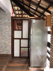 a metal refrigerator in a room with a brick wall at Flat Maresias in Maresias