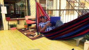 a woman sitting in a hammock with a laptop at Max Rooms in San Ignacio