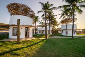 una casa con palmeras en el patio en VentoVinte Beach Club, en Flecheiras