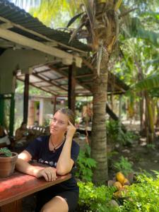 Eine Frau, die auf einem Tisch mit der Hand auf dem Kopf sitzt. in der Unterkunft Casa Esmeralda in Moyogalpa