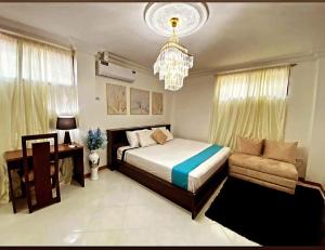 ein Schlafzimmer mit einem Bett, einem Sofa und einem Kronleuchter in der Unterkunft Habitacion Master a cinco minutos del aeropuerto in Guayaquil