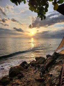 um pôr-do-sol numa praia com rochas e o oceano em Rincon Retreat,- Close to beach/ Ocean Front em Corcega