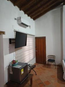 uma sala de estar com uma televisão de ecrã plano e uma cadeira em Hotel Boutique Casa Gerar em Santa Cruz de Mompox