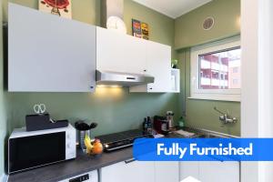 a kitchen with white cabinets and a microwave at The Green House - Private Parking and Balcony in Milan