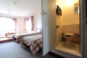 a bedroom with two beds and a toilet and a window at Hotel Moc in Myoko