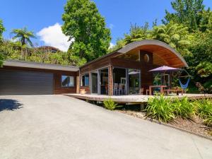 a large house with an umbrella and a driveway at FlaxWater Lake Tarawera in Lake Tarawera