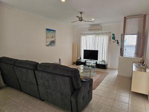 a living room with a couch and a flat screen tv at Koola Beach Apartments Bargara in Bargara