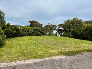 a grassy yard with a bench in front of a house at SUMMER DAYSIES - Pet Friendly WiFi in Robe