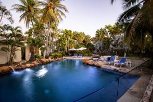 a swimming pool with blue chairs and palm trees at Seagulls in Townsville
