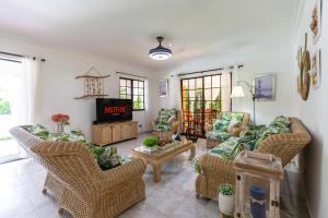 un soggiorno con sedie in vimini e TV di Villa At Metro Country Club With Private Pool a San Pedro de Macorís