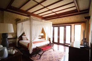 a bedroom with a canopy bed in a room with windows at Balinese Villa in Berastagi in Berastagi