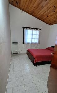 um quarto com uma cama vermelha e uma janela em Casa Bis em Villa Gesell