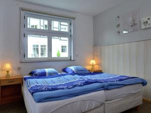 Un dormitorio con una cama con almohadas azules y una ventana en Cozy holiday home with balcony near Winterberg, en Elpe