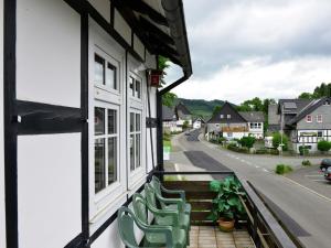 uma varanda com cadeiras verdes numa casa com uma rua em Cozy holiday home with balcony near Winterberg em Elpe