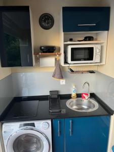 a kitchen with a washing machine and a microwave at Studio Harmonie Vue panoramique-Location saisonnière-10mn du tombolo-100m de la plage-Restaurants à proximité Randonnée-Surf-Plage in La Trinité