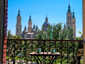 a table with two cups on a balcony with a view of a city at Front Views To El Pilar ComoTuCasa in Zaragoza
