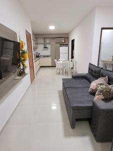 a living room with a black couch and a kitchen at Guaibim in Guaibim