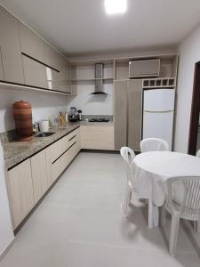 a kitchen with a table and a white table and chairs at Guaibim in Guaibim