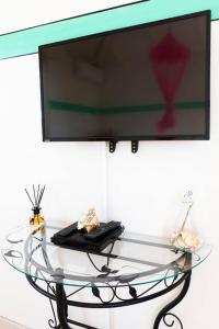 a glass table with a flat screen tv on a wall at Studio Soleil Couchant in Pointe-Noire