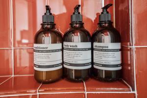 three bottles of shampoo on a shelf in a bathroom at Strawberry Container @ EADO Juice Box in Houston