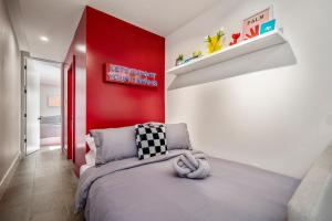 um quarto com uma cama e uma parede vermelha em Strawberry Container @ EADO Juice Box em Houston