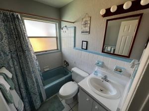 a bathroom with a sink and a toilet and a mirror at Surfside Suites in Cocoa Beach