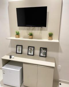a desk with a tv on a wall with plants at Origem in Mamanguape