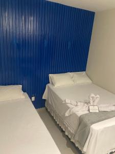 two beds in a room with blue curtains at Origem in Mamanguape