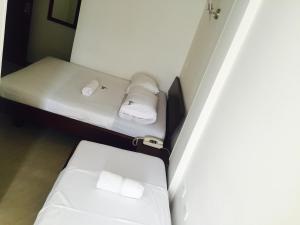 two beds in a small room with white sheets at Hotel Preferencial Class in Bucaramanga