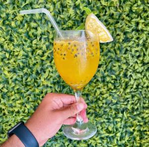 a person holding a glass with a lemon slice in it at Origem in Mamanguape